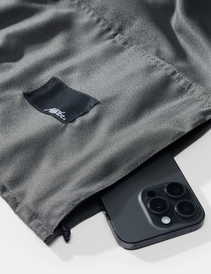 Matador NanoDry™ Packable Beach Towel - black phone on a gray fabric background