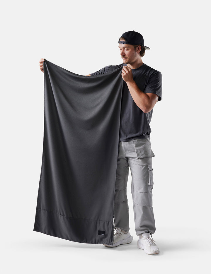 Matador NanoDry™ Packable Beach Towel - man holding a large gray fabric against a white background