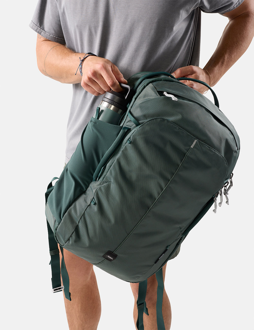 Matador 30L Carry-On Travel Pack in Juniper - pulling water bottle out of green backpack