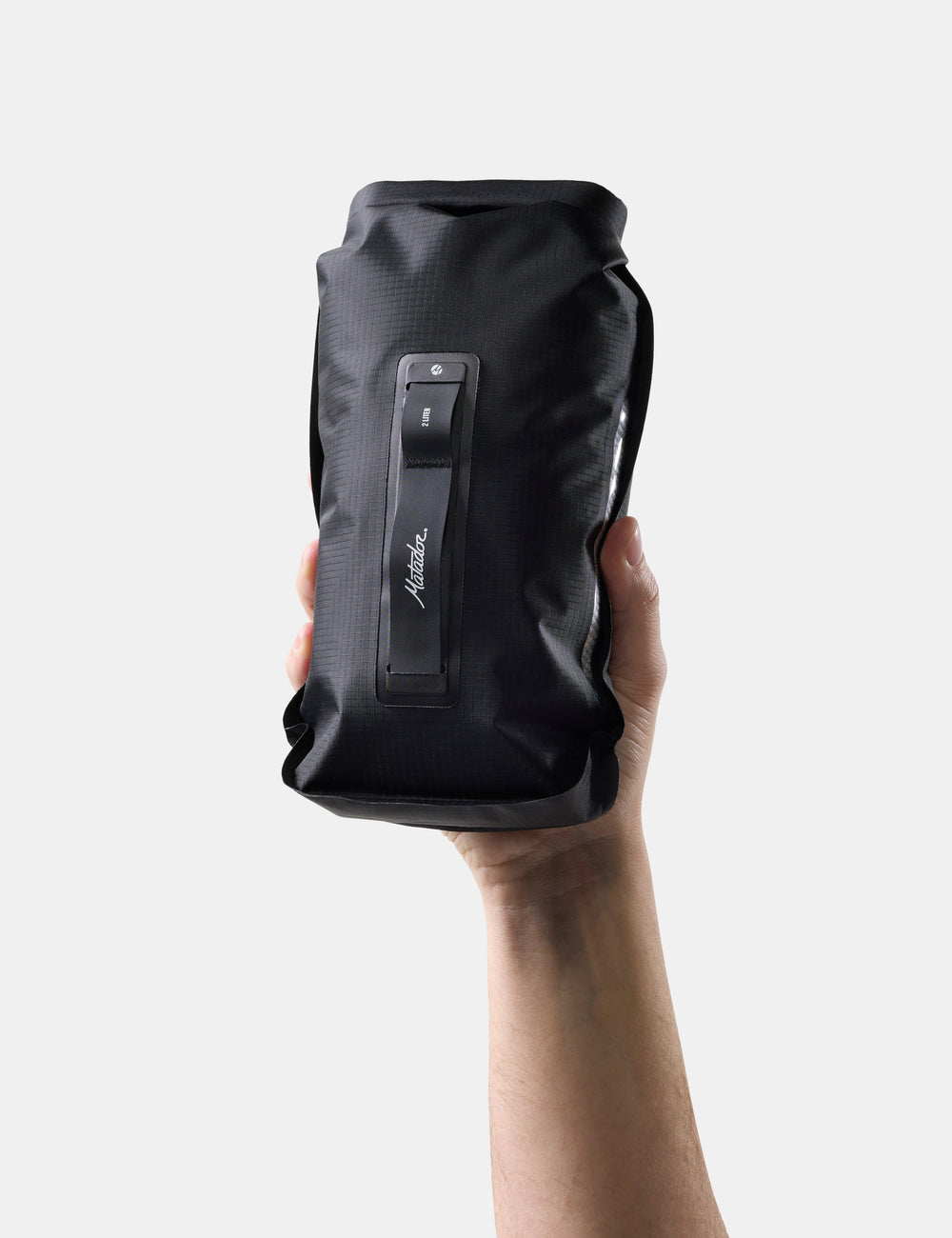 Matador FlatPak Drybag 2L (V2) in Black - black dry bag held by a hand on a white background