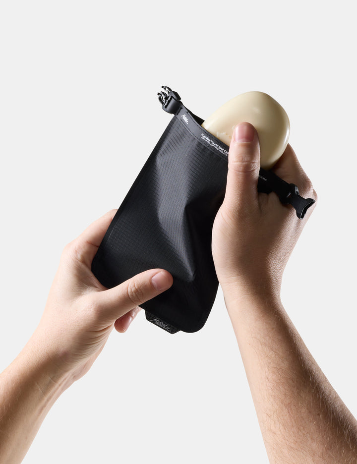 Matador FlatPak Travel Soap Bar Case (V2) in Black - person holding Black soap bar case with soap inside against a light background