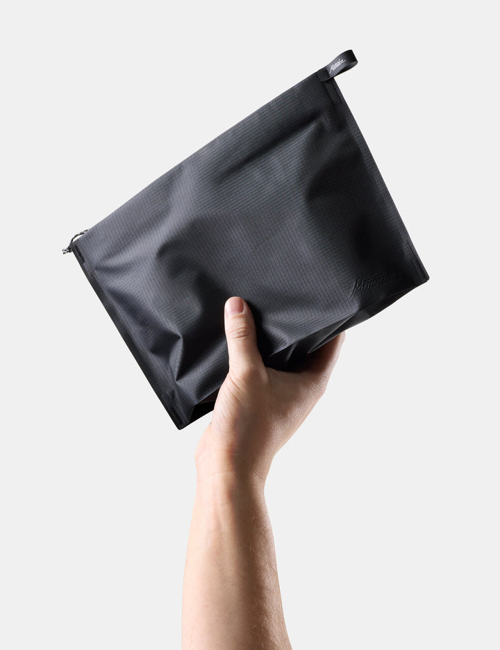 Matador FlatPak Zipper Toiletry Case (V2) in Black - hand holding a Black zippered toiletry case against a light gray background