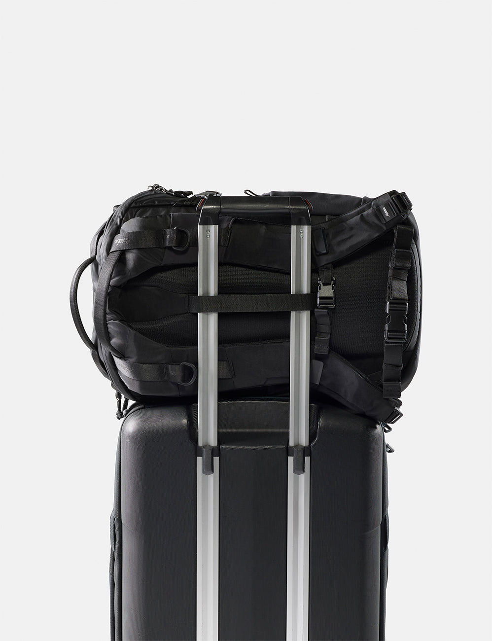 Matador 24L Adventure Pack in Black - black backpack attached to a black suitcase on a white background