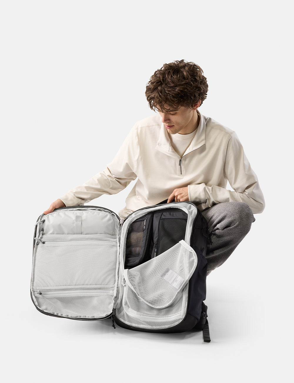 Matador 35L Global Travel Pack in Black - person unpacking a large backpack on a white background