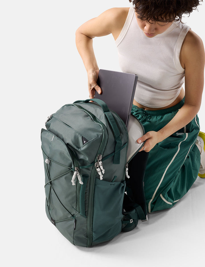 Matador 35L Global Travel Pack in Juniper - person organizing items in a green backpack on a white background