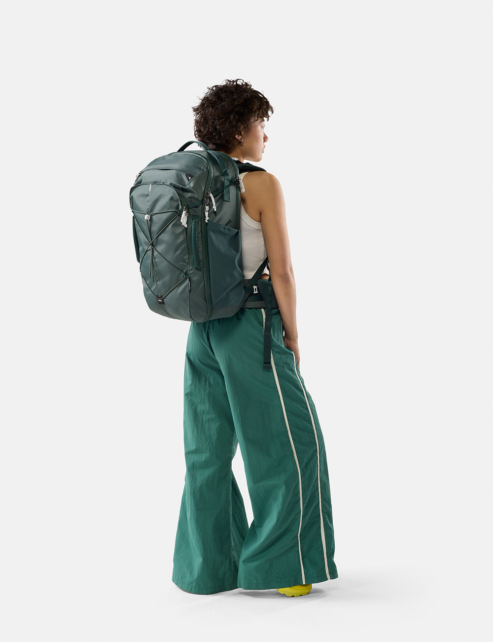 Matador 35L Global Travel Pack in Juniper - person wearing a green backpack and green pants on a white background