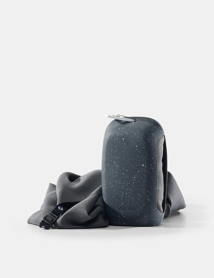 Matador NanoDry Towel - Large 132 x 60cm in Black Granite - nanodry towel placed next to silicone case on white background