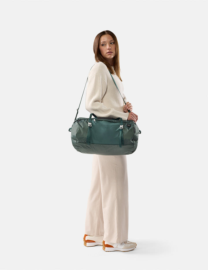 Matador 30L Packable Duffel in Juniper - woman holding a green duffel bag against a white background
