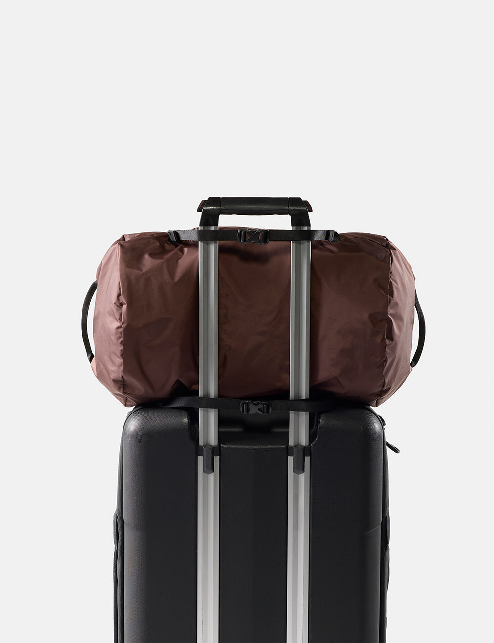 Matador 30L Packable Duffel in Garnet - garnet duffel bag secured to a black suitcase with straps on a light gray background