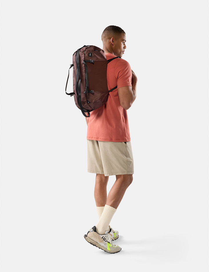 Matador 30L Packable Duffel in Garnet - man wearing a garnet backpack on a white background