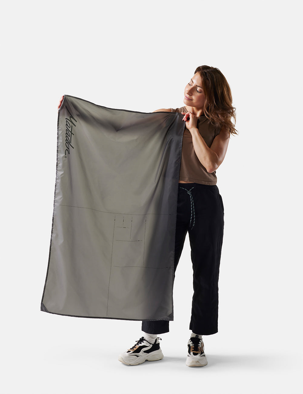 Matador Mini Pocket Blanket™ 4.0 - 110 x 70cm in Ghost Grey - person holding a large gray fabric item on a white background