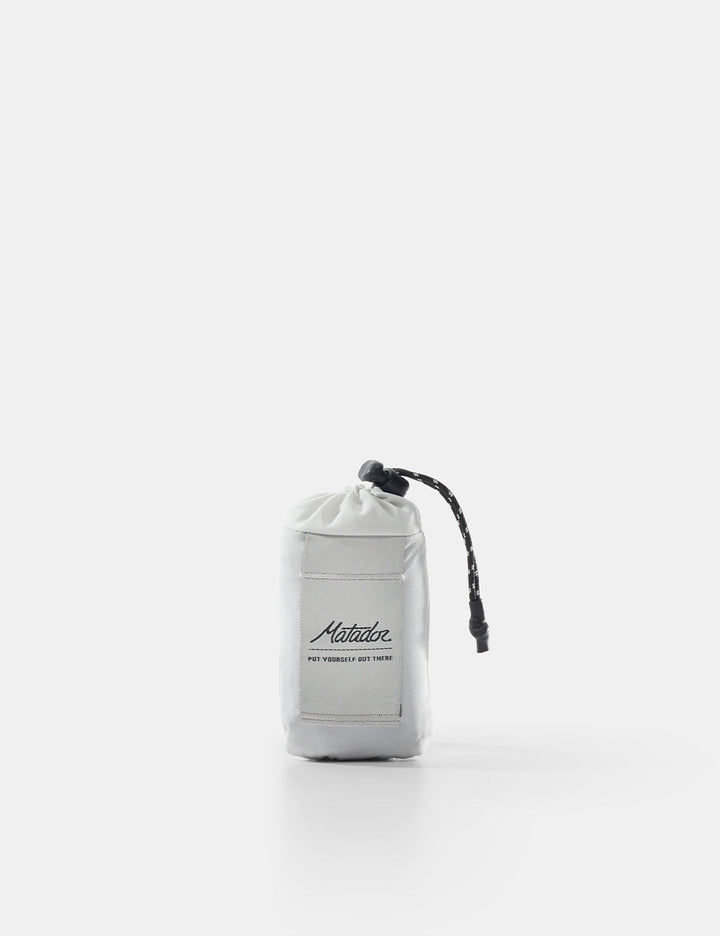 Matador Mini Pocket Blanket™ 4.0 - 110 x 70cm in Ghost Grey - white drawstring bag with black branding on a white background