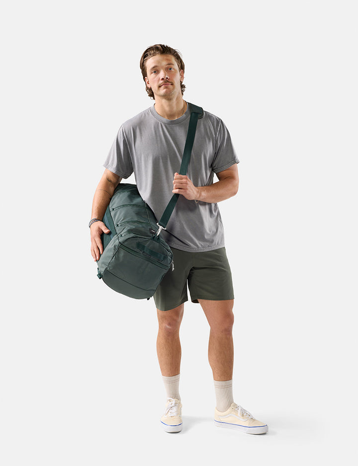 Matador 45L SEG Hybrid Travel Pack in Juniper - man holding a green duffel bag against a white background