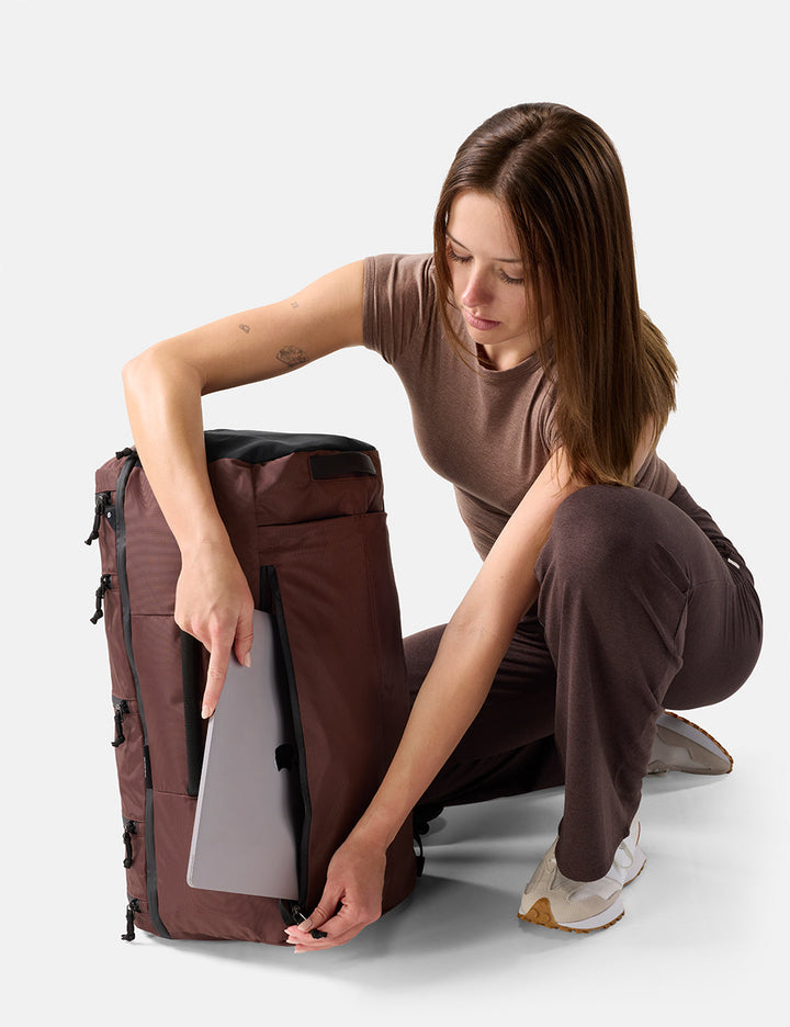 Matador 45L SEG Hybrid Travel Pack in Garnet - woman organizing a large Garnet backpack on a white background