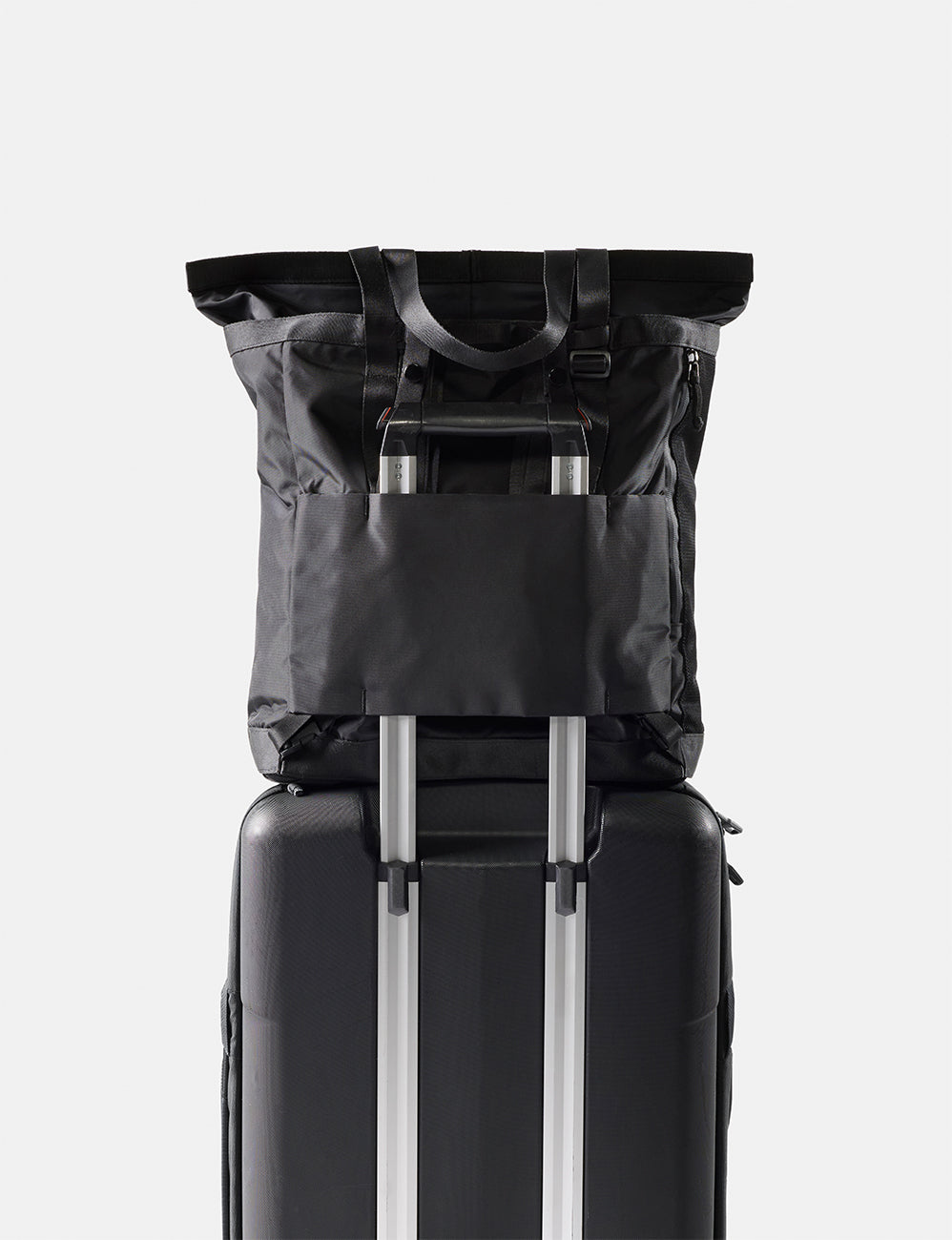 Matador 24L Tote Pack in Black - black tote pack on top of a suitcase with a white background