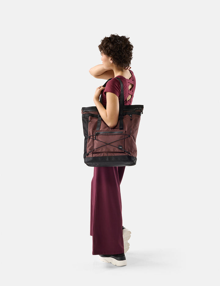 Matador 24L Tote Pack in Garnet - woman carrying a garnet tote on a white background