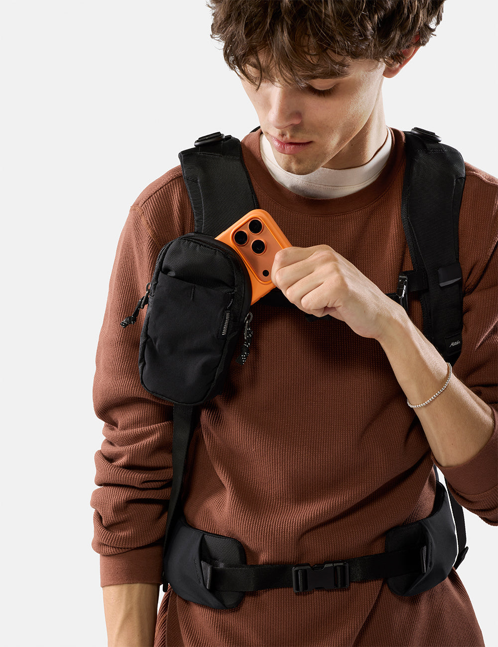Matador Speed Stash (V2) in Black - person wearing a brown sweater pulling orange phone out of black speed stash