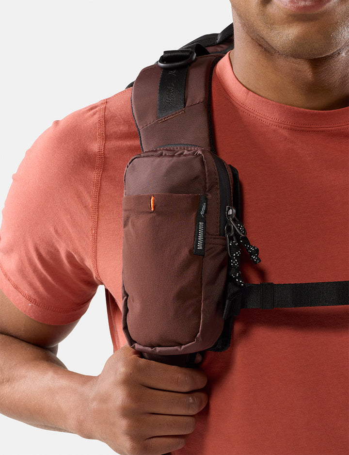 Matador Speed Stash (V2) in Garnet - person wearing a garnet crossbody bag on a plain background