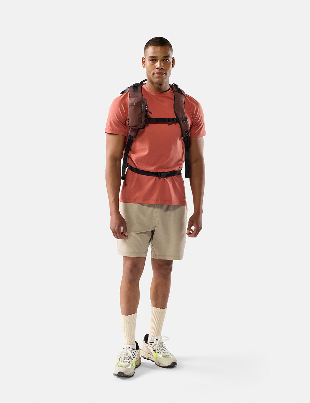 Matador Speed Stash (V2) in Garnet - man wearing a red shirt, beige shorts, and a garnet backpack on a white background